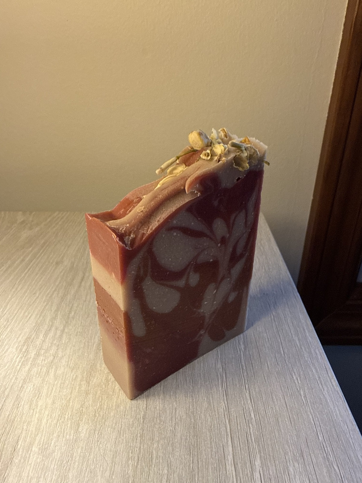 Original photograph of Orchard Reserve soap showing its swirls, sculpted top, and dried jasmine blossoms.